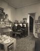 In this image, two men sit at a piano. Their backs are facing the camera.