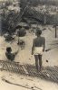 In this image, a man faces away from the camera. He is shirtless and overlooking a beach with wooden walkways.