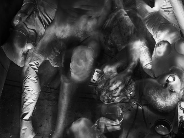 This photograph shows the crowded floor of an apartment where naked bodies and dolls are strewn across the ground.