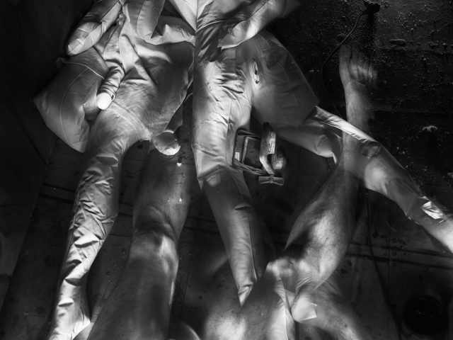 This photograph shows the ghostly limbs of figures sprawled across the wooden floor.