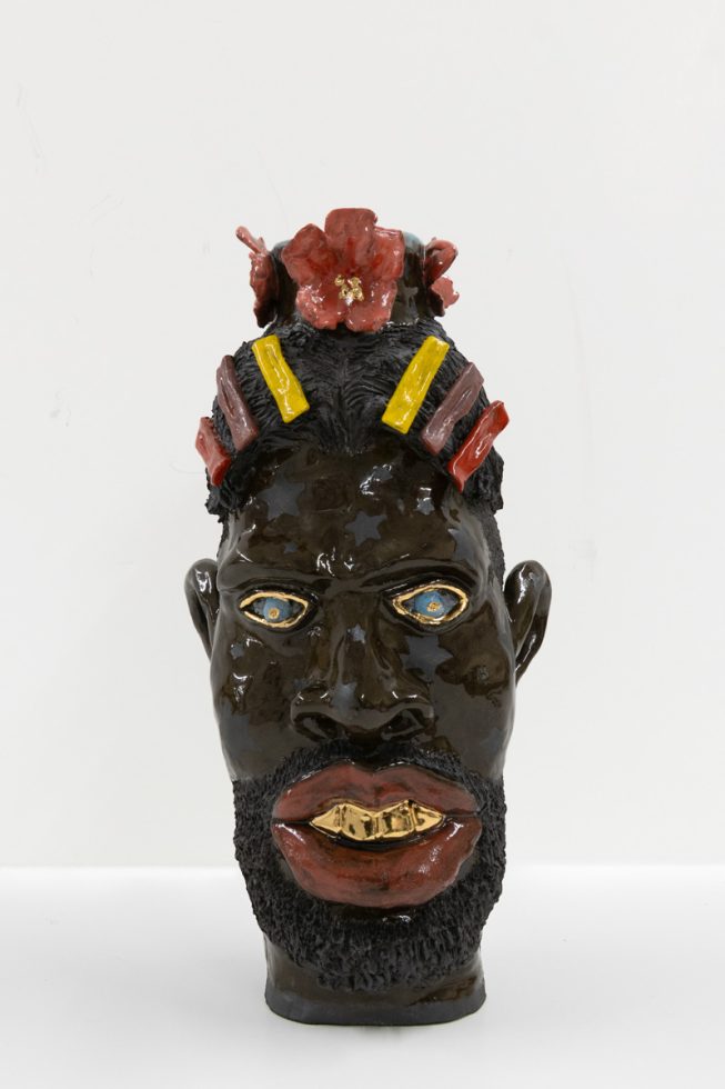 A ceramic vessel with dark brown glazing depicting a man's head.