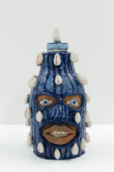 This is a small ceramic sculpture painted with dark and light blue stripes. Small shells rise from its sides.