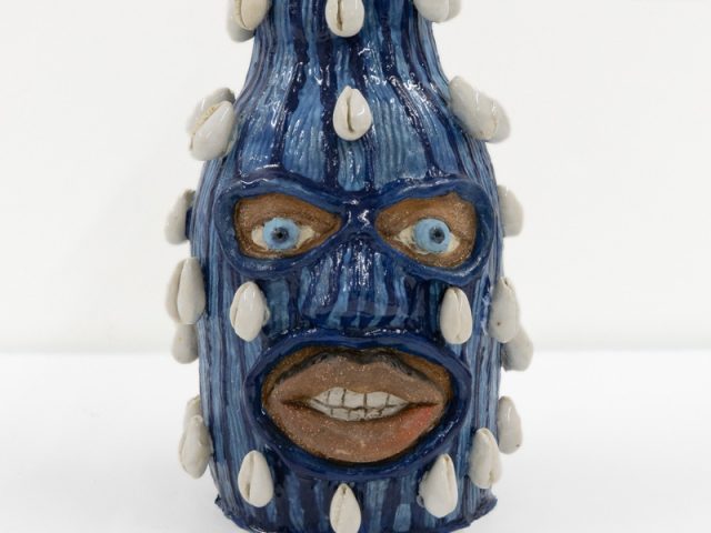 A ceramic vessel depicting a head wearing a balaclava.