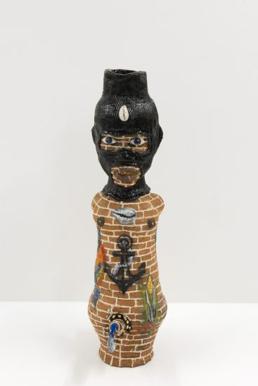 A ceramic vessel depicting a human figure with skin resembling bricks.