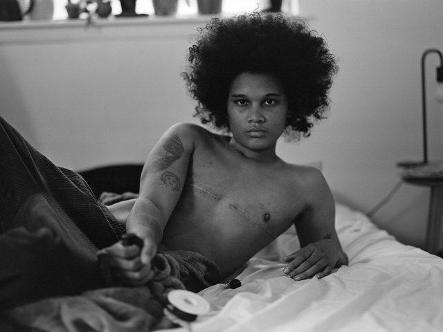 A black-and-white photograph of a person reclining without a shirt.