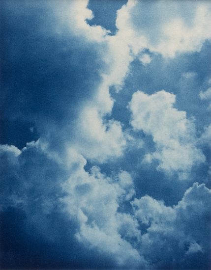 This color photograph shows the sky filled with puffy white clouds.