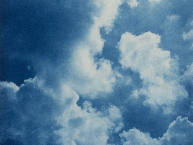 This color photograph shows the sky filled with puffy white clouds.