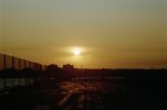This color photograph shows a yellow sunset, setting above the skyline of New York City.