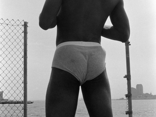 This black and white photograph shows a man's back, facing away from the camera.