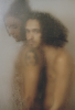 This photograph shows two figures seen from behind a blurred glass. They are naked.