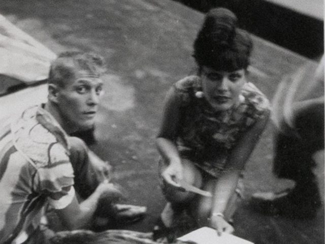 This black and white photograph shows a man and a woman crouching on the ground.