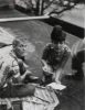 This black and white photograph shows a man and a woman crouching on the ground.