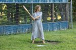 This color photograph shows a girl holding a homemade bat.