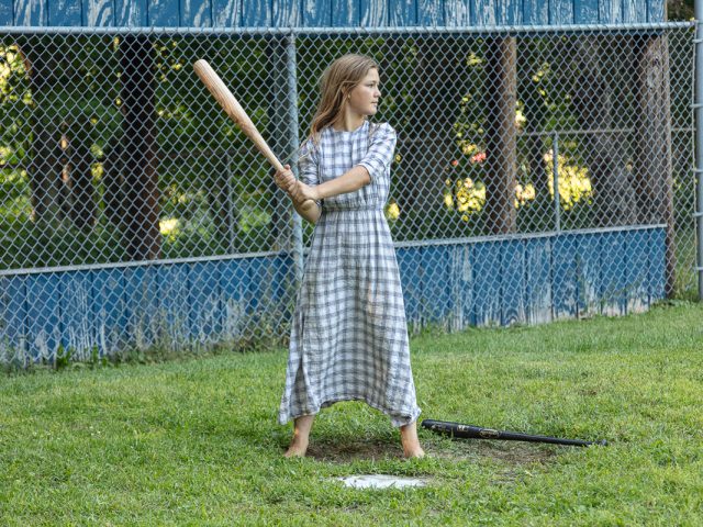 This color photograph shows a girl holding a homemade bat.