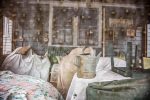 This color photograph shows a screened in porch with some chairs and a watering can.