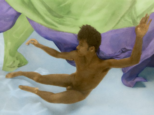 This photograph shows a man floating underwater in a pool with billowing green and purple fabric.