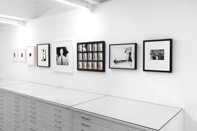This photograph shows the walls of a gallery where framed photographs hang in a line.