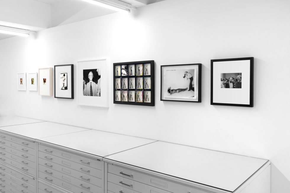 This photograph shows the walls of a gallery where framed photographs hang in a line.