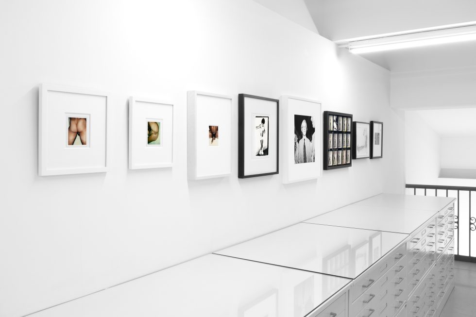 This photograph shows a series of photographs on the white walls of a gallery.