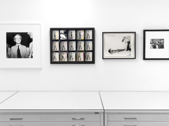 This photograph shows framed black and white photographs on the walls of a gallery.