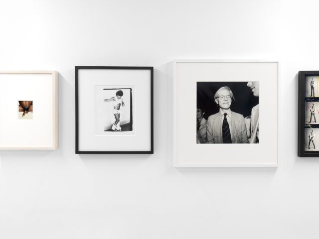 This photograph shows a series of black and white photographs hanging on the walls of a gallery.