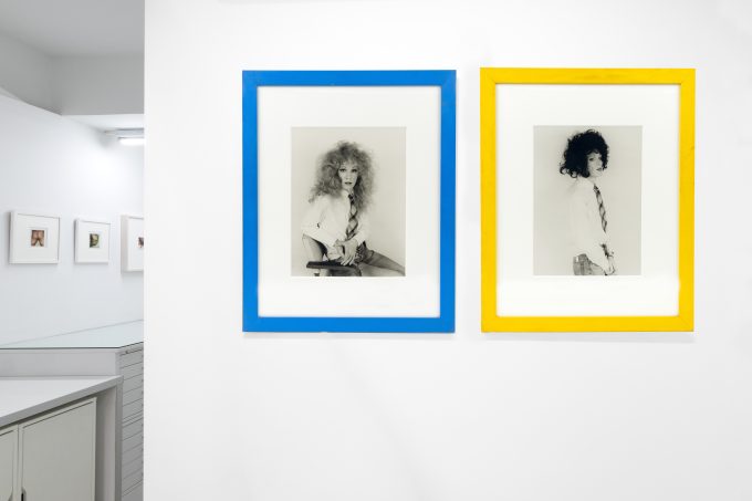 This photograph shows black and white photographs of men in wigs framed in bright colors.