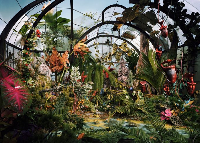 A color photo of an overgrown and forgotten botanical garden constructed from paper, clay, and other materials.