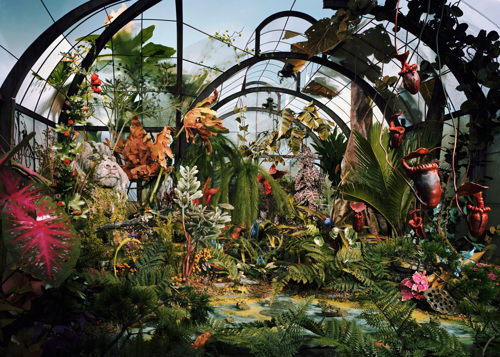 A color photo of an overgrown and forgotten botanical garden constructed from paper, clay, and other materials.