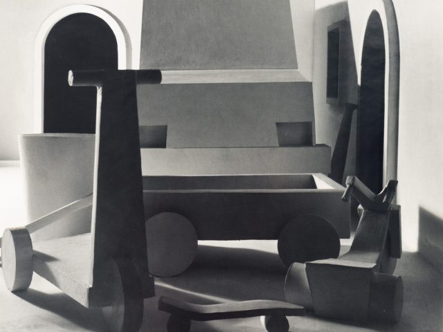 This black and white photograph shows a large typewriter sitting in an open room.