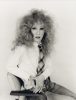 This image shows a person sitting in a chair who wears a very frizzy wig.