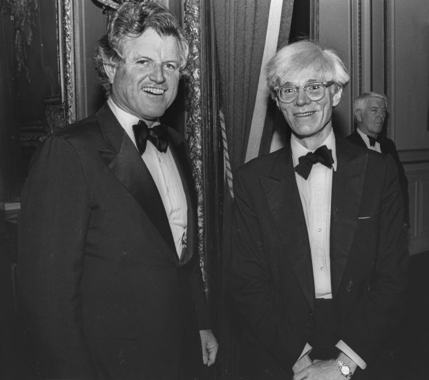 This is a black and white photograph of Andy Warhol and Ted Kennedy at an event.