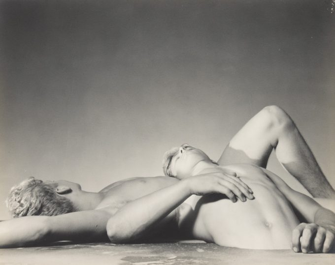 This black and white photograph shows two men lying on top of one another.