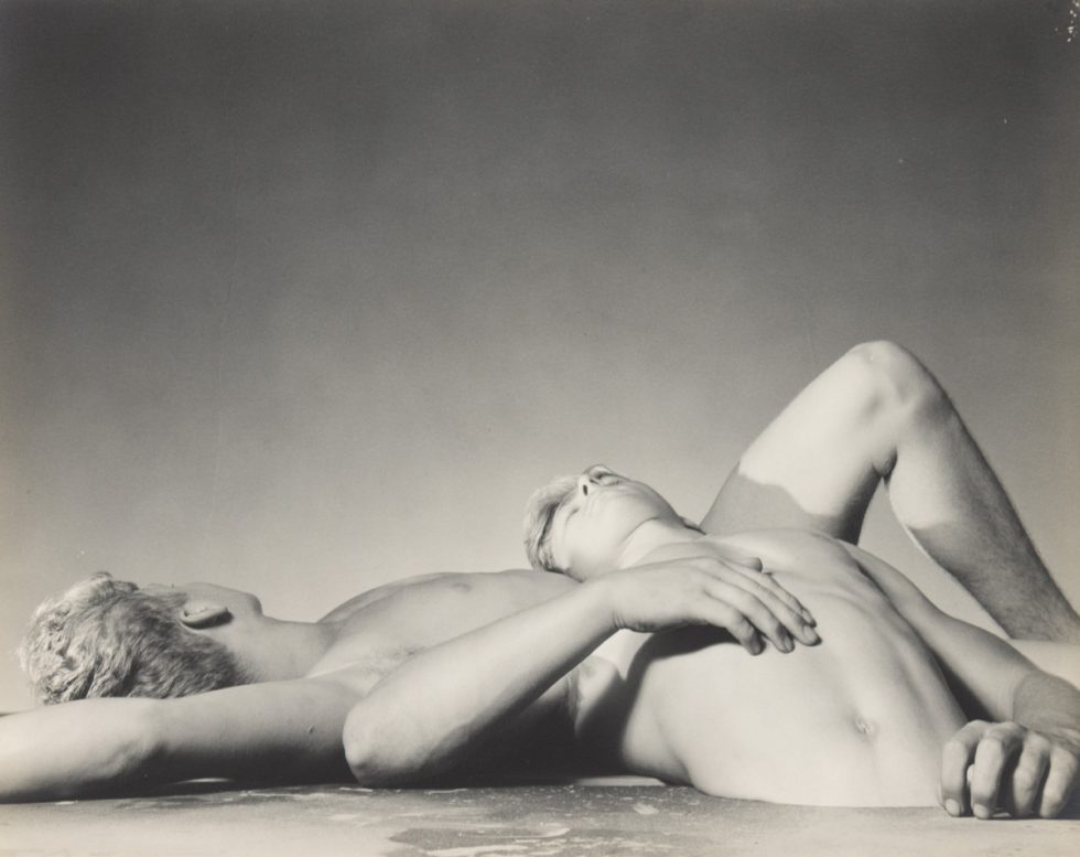 This black and white photograph shows two men lying on top of one another.