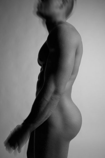 This black and white photograph shows a man's silhouette, facing sideways against a grey background.