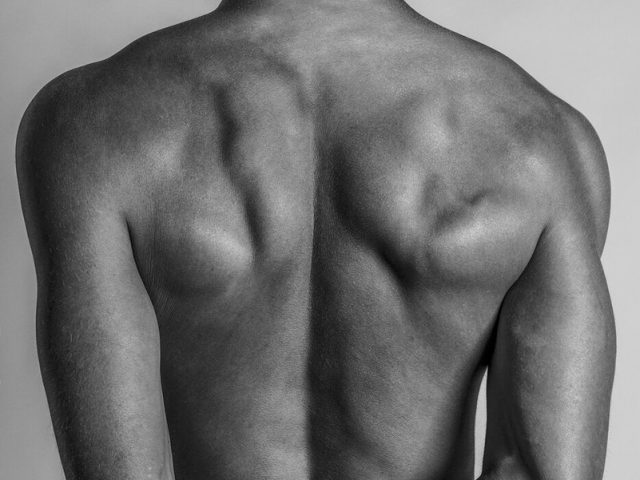 This black and white photograph shows a man's back, shining with light.
