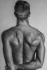 This black and white photograph shows a man's back, shining with light.